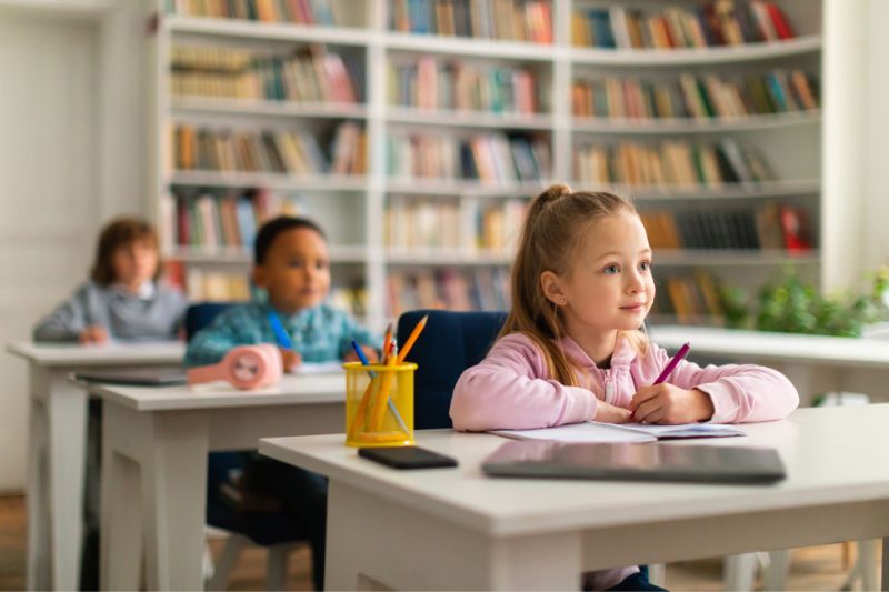 Niños en un aula escolar inclusiva, recibiendo educación en un ambiente adaptado a diferentes necesidades educativas.
